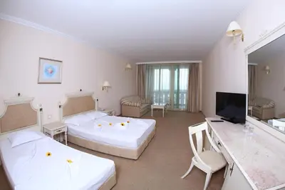 a large room with two beds and a television at Duni Marina Beach Hotel - All Inclusive in Sozopol