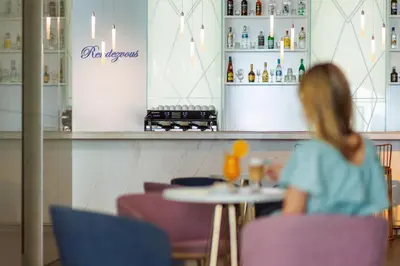 a woman sitting at a table in a restaurant at Secrets Sunny Beach Resort and Spa - Premium All Inclusive - Adults Only in Sunny Beach