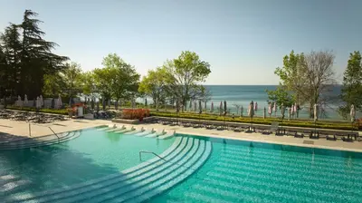 a swimming pool with chairs and the ocean in the background at Secrets Sunny Beach Resort and Spa - Premium All Inclusive - Adults Only in Sunny Beach