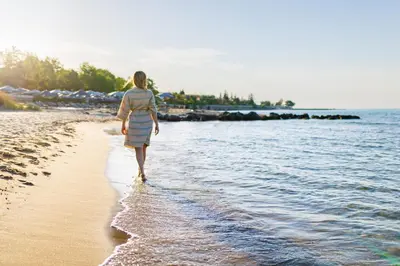 a woman walking on the beach near the water at Secrets Sunny Beach Resort and Spa - Premium All Inclusive - Adults Only in Sunny Beach