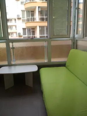 a green bench in a room with a window at Виктория in Pomorie