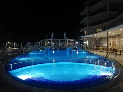 a large blue swimming pool at night at DEA Pasavan Apartments in Ravda