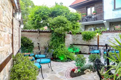 a garden with chairs and a stone wall at Kirios Hotel in Nesebar