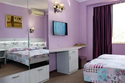 a purple bedroom with two beds and a mirror at Kirios Hotel in Nesebar