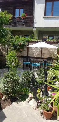 a patio with a table and an umbrella and plants at Kirios Hotel in Nesebar