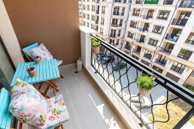 a balcony with a blue table and chairs and a building at Pomorie Seaside Apartments in Pomorie