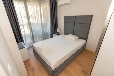 a bedroom with a bed and a large window at Pomorie Seaside Apartments in Pomorie