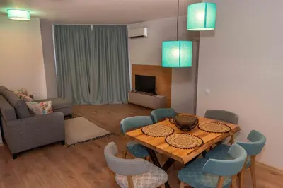 a living room with a wooden table and blue chairs at Pomorie Seaside Apartments in Pomorie
