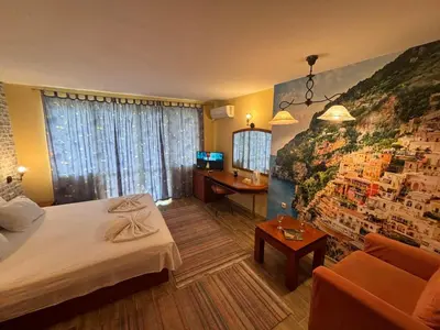 a hotel room with a bed and a painting on the wall at Family Hotel Vaso in Varna City