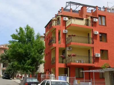 a red building with cars parked in front of it at Виктория Созопол in Sozopol