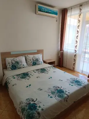 a bedroom with a bed with a floral bedspread at Виктория Созопол in Sozopol