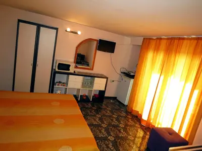 a bedroom with a bed and a yellow curtain at Family Hotel Lebed in Nesebar