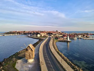 a bridge with a windmill next to the water at Family Hotel Lebed in Nesebar