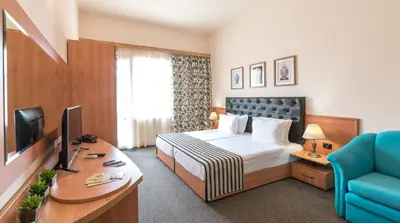 a hotel room with a bed and a desk at Lotus Family Hotel - Free Parking in Sunny Beach