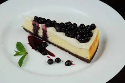 a piece of cake with blueberries on a white plate at Lotus Family Hotel - Free Parking in Sunny Beach