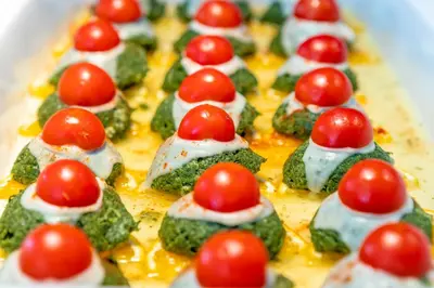 a tray of food with tomatoes on top of broccoli at Diamond Hotel - All Inclusive in Sunny Beach