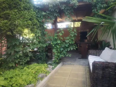 a garden with a couch in a room with plants at Къща Нанси in Sunny Beach