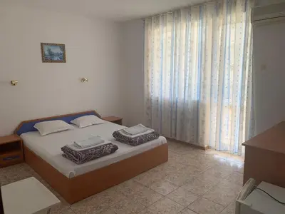 a bedroom with a bed and a large window at Къща Нанси in Sunny Beach
