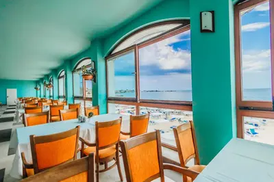 a dining room with tables and chairs and a view of the ocean at Mirage Hotel in Nesebar