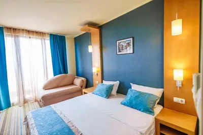 a hotel room with a bed and a chair at Mirage Hotel in Nesebar