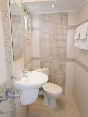 a bathroom with a toilet and a sink at Family Hotel White House in Pomorie
