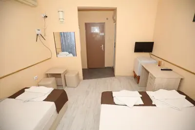 a room with two beds and a desk and a television at Family Hotel White House in Pomorie