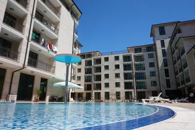 a swimming pool with a blue umbrella and some buildings at Amadeus Lux - Menada Apartments in Sunny Beach