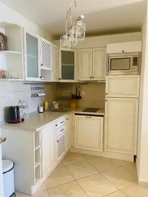 a kitchen with white cabinets and a chandelier at FLORES GARDEN SEA VIEW APARTMENT WITH BALCONY in Chernomorets