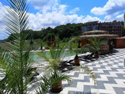 a resort with a pool with palm trees and a building at Allure Beach Resort Aparthotel in Primorsko