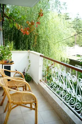 a balcony with a rattan chair and a fence at Guest House Barbov in Obzor