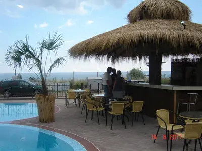 two people sitting at a restaurant next to a pool at Laguna Beach Hotel in Ravda