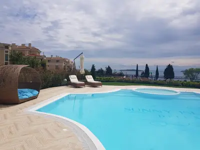 a large blue swimming pool with two chairs at Azur Apartment Deluxe in Chernomorets