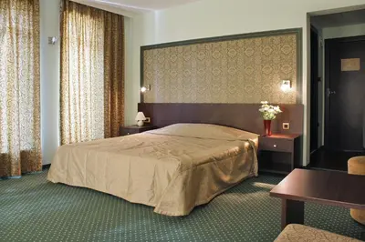 a bedroom with a large bed and two tables and a chair at Hotel Dukov in Obzor
