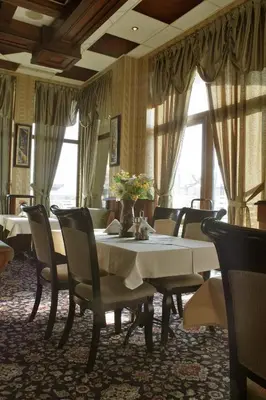 a dining room with a table and chairs and windows at Hotel Dukov in Obzor