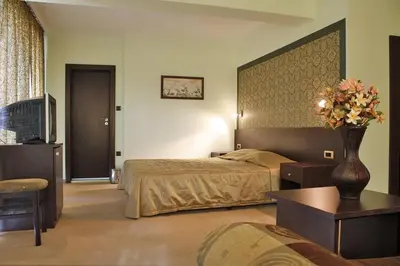a hotel room with a bed and a vase of flowers at Hotel Dukov in Obzor