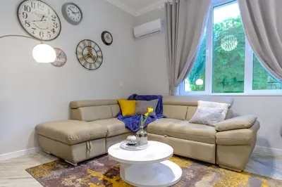 a living room with a couch and clocks on the wall at The Olive Green House - City Center - Free Parking in Burgas City