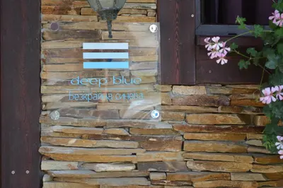 a sign on the side of a brick wall at Deep Blue Guest House in Sozopol