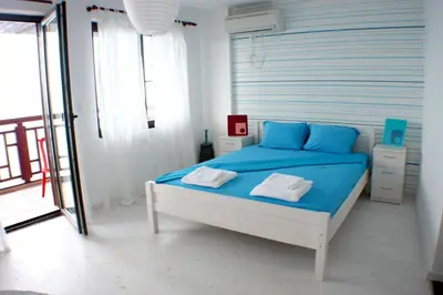 a bedroom with a bed with blue sheets and a window at Deep Blue Guest House in Sozopol