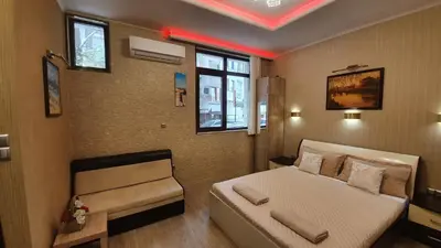 a bedroom with a bed and a couch and a window at Deluxe Studios City Center in Burgas City