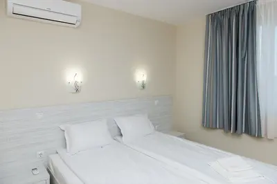 a white bed with two pillows and a window at Hiora Apartments Vasiliko in Tsarevo