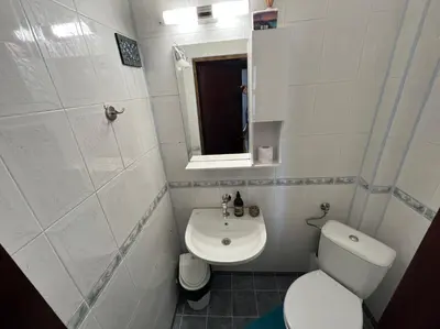 a white bathroom with a toilet and a sink at Izgrev Sarafovo in Burgas City