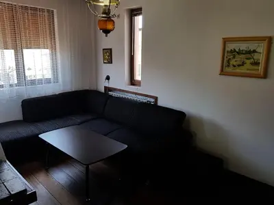 a living room with a black couch and a table at Апартамент Емилия in Sozopol