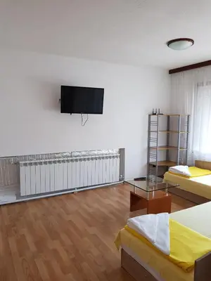 a room with two beds and a flat screen tv on the wall at Апартамент Емилия in Sozopol