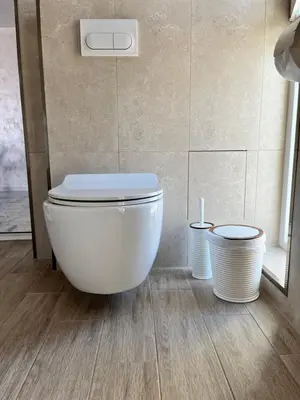 a white toilet in a bathroom with two trash cans at Ancient well in Sozopol