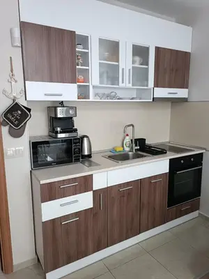 a kitchen with wooden cabinets and a sink and a microwave at Megi Luxury Apartments in Pomorie