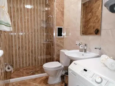 a bathroom with a toilet and a sink and a shower at Megi Luxury Apartments in Pomorie