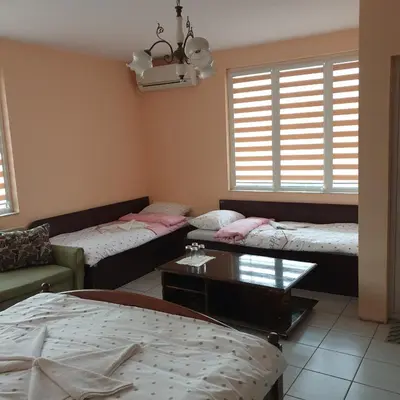a living room with three beds and a table at Къща за гости Оазис in Pomorie