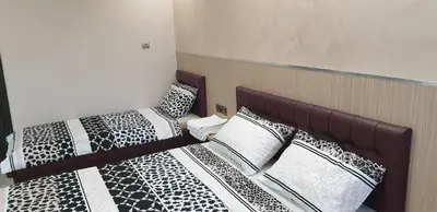 two beds with black and white pillows in a room at Къща за гости Оазис in Pomorie