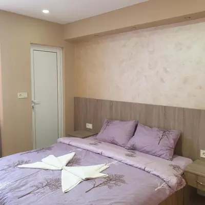a bedroom with a purple bed with two white towels on it at Къща за гости Оазис in Pomorie