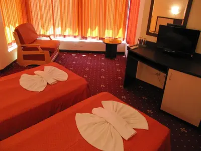 a hotel room with two beds and a chair and a television at Maverick Hotel in Sunny Beach